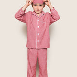 Child wearing red checkered pajama set with matching headband on a beige background