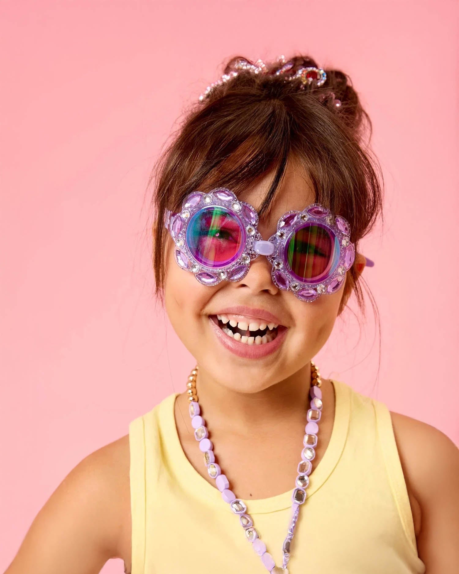 a little girl smiling and wearing sparkly goggles