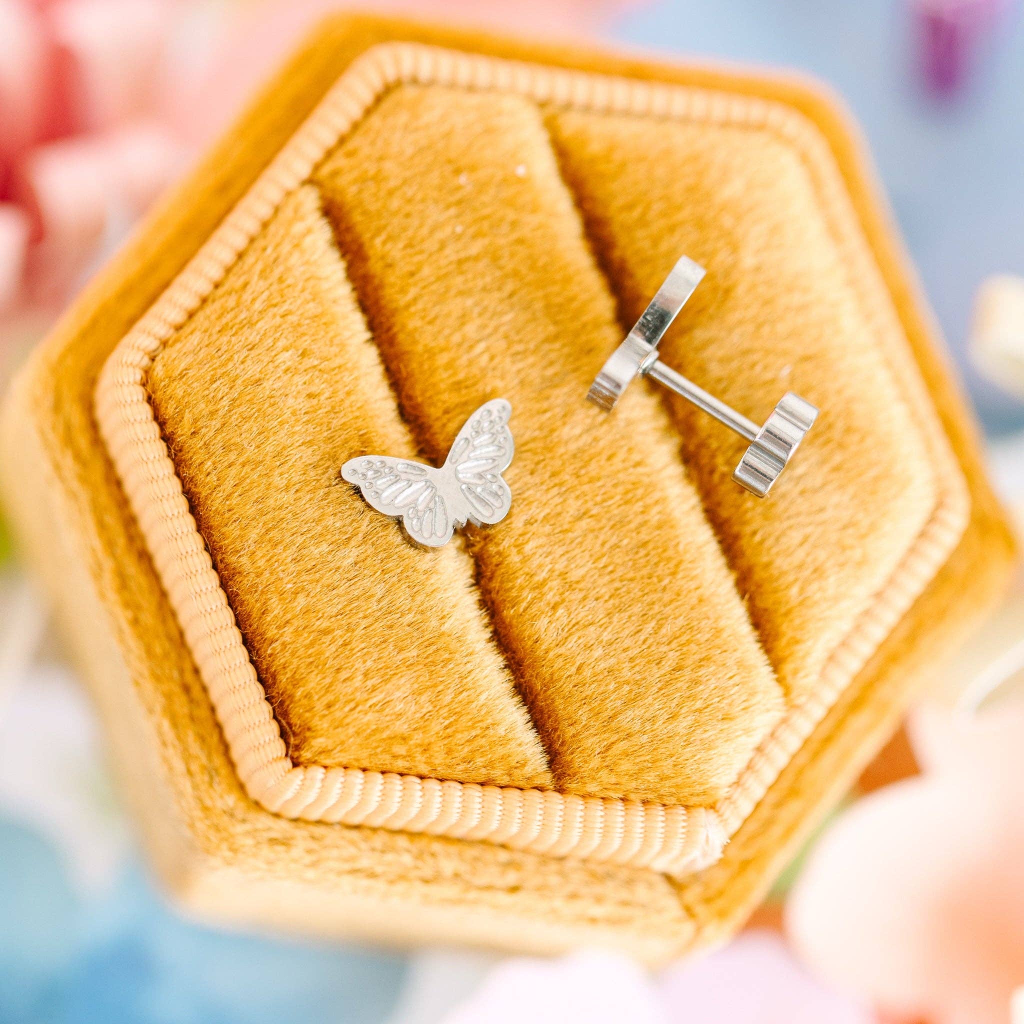 Butterfly-shaped earrings in a hexagonal yellow jewelry box.