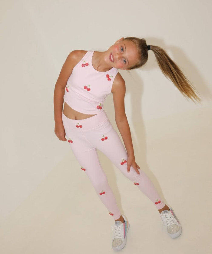 Young girl wearing a pink outfit with cherry patterns on a beige background