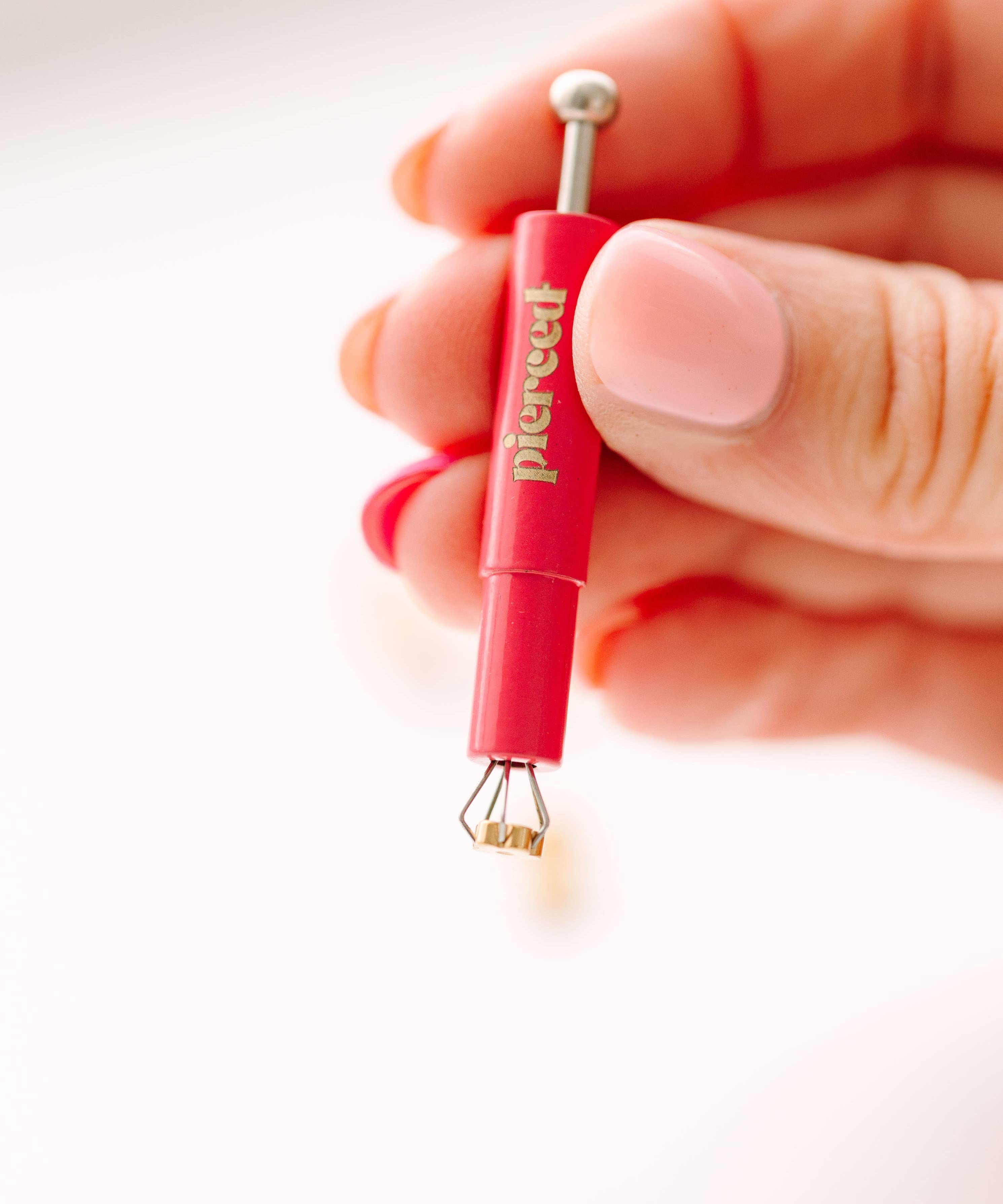 earring back tool held by a hand 
