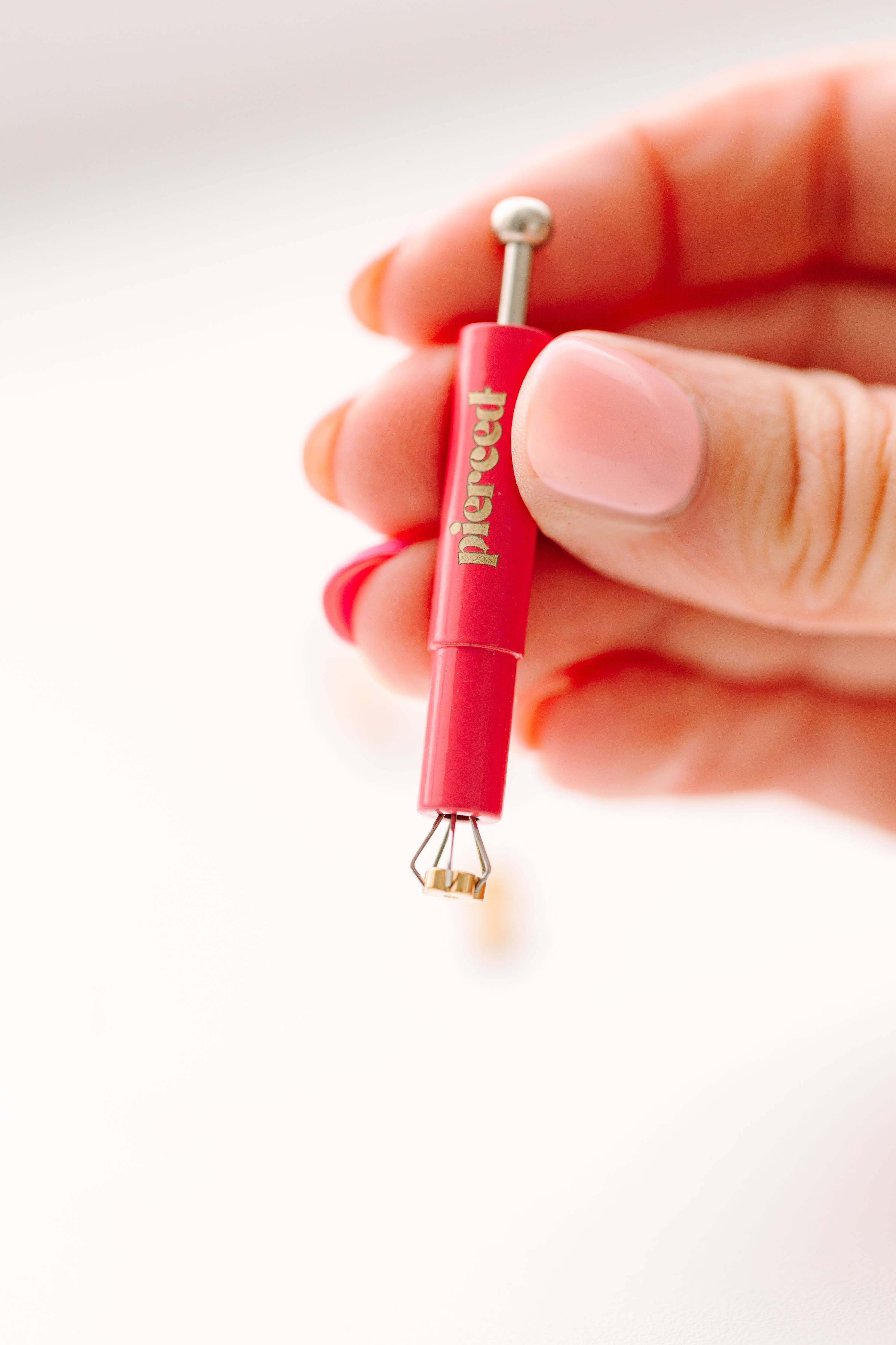 earring back tool held by a hand 
