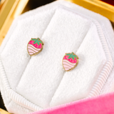 Strawberry-shaped earrings in a gold frame on a white cloth