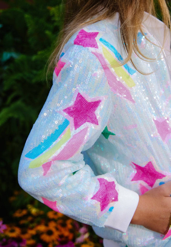 Sequined jacket with star and rainbow patterns worn by a person outdoors.