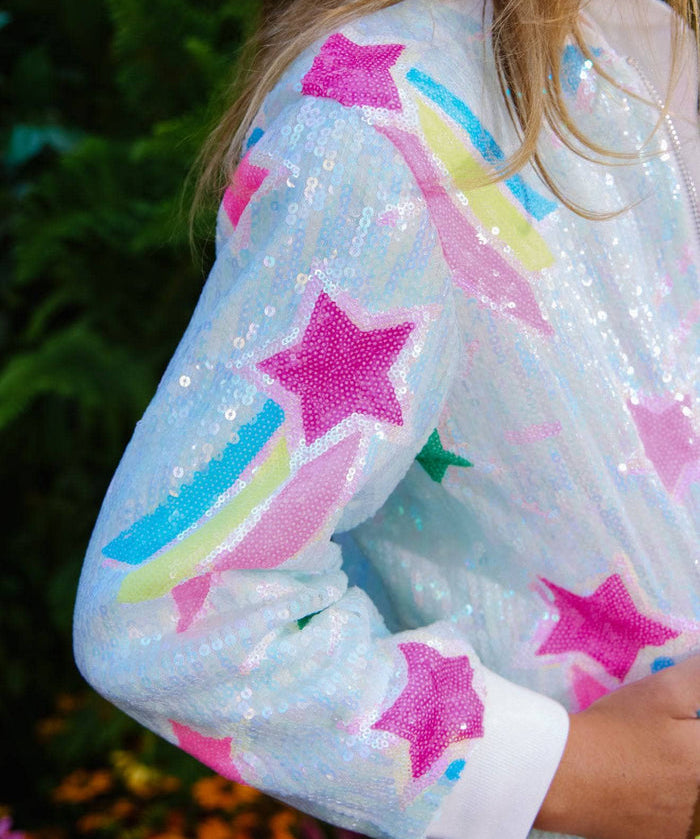 Sequined jacket with star and rainbow patterns worn by a person outdoors.