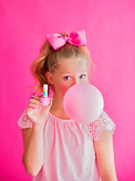 girl blowing a bubble and holding pink nail polish