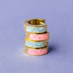 Stack of colorful hoop earrings on a purple background