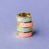 Stack of colorful hoop earrings on a purple background