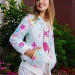 Young girl wearing a colorful star-patterned jacket in an outdoor setting with flowers and plants.