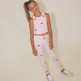 Young girl wearing a pink outfit with cherry patterns on a plain background