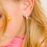 Close-up of a person wearing a pink earring with a heart and key charm design.