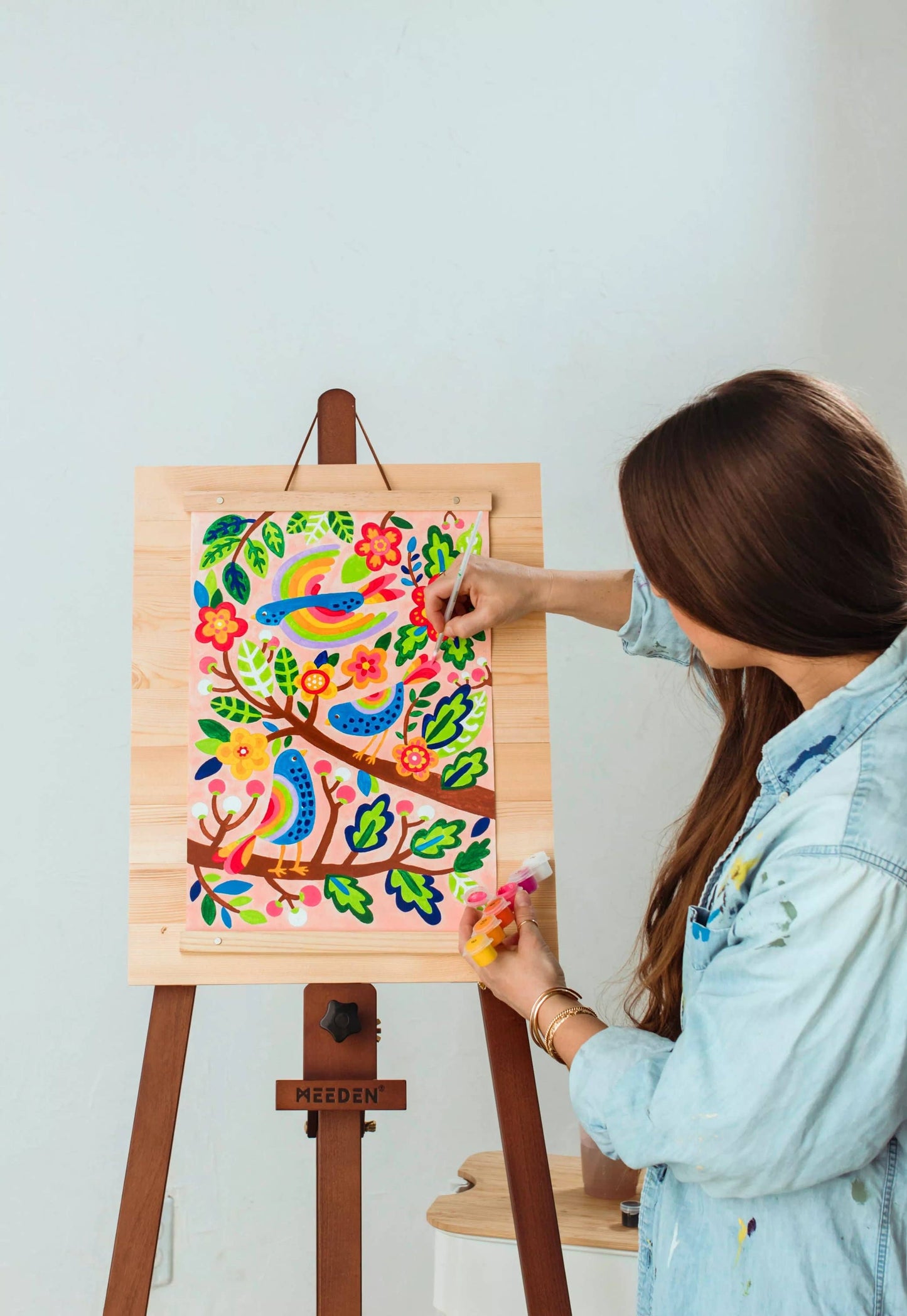 Girl painting the bird canvas on an easel