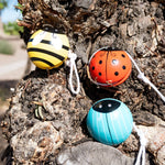 Three colorful ladybug-shaped yo-yos on a tree trunk.