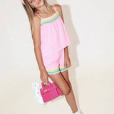Young girl in a pink outfit with colorful accents holding a pink bag on a white background