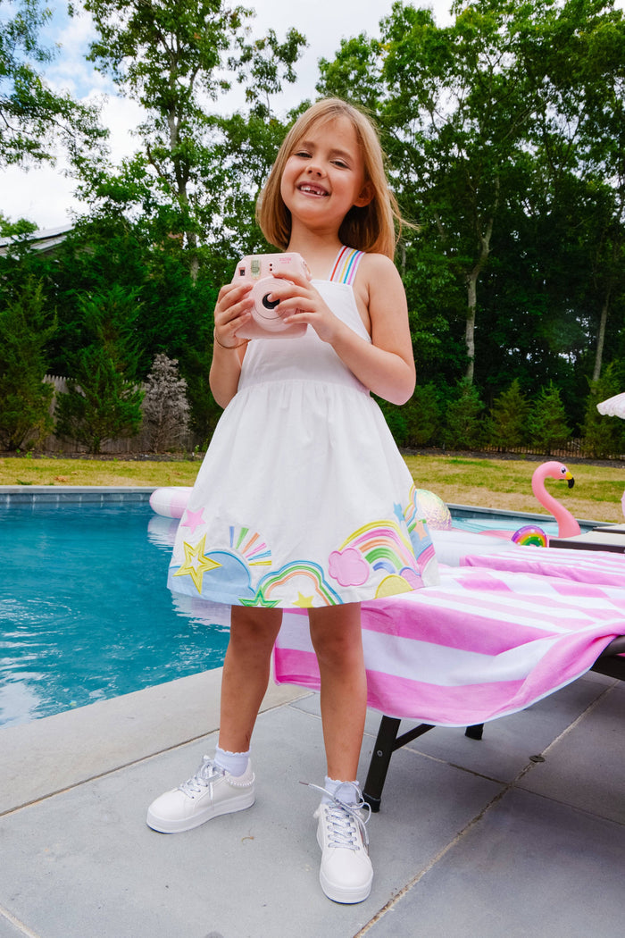 Young girl in a white dress with colorful designs by a pool