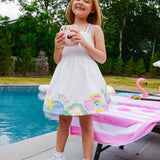Young girl in a white dress with colorful designs by a pool
