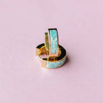 Gold hoop earrings with opal centers with pink background