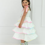 Young girl wearing a white dress with colorful trim and sparkly boots on a white background