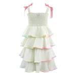 White tiered dress with colorful trim and pink straps on a white background