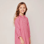 Young girl wearing a red checkered dress against a plain background