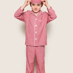 Child wearing red checkered pajama set with matching headband on a beige background