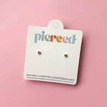 Pair of earrings on a 'pierced' branded card against a pink background