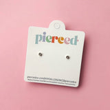 Pair of earrings on a 'pierced' branded card against a pink background