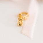 Gold earring with leaf design on a light background