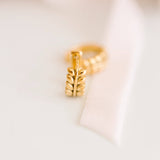 Gold earring with leaf design on a light background