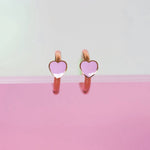 Heart-shaped earrings with pink hearts on a light gray and pink gradient background