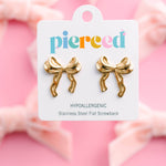 Gold bow-shaped earrings on a 'pierced' branded card against a pink background