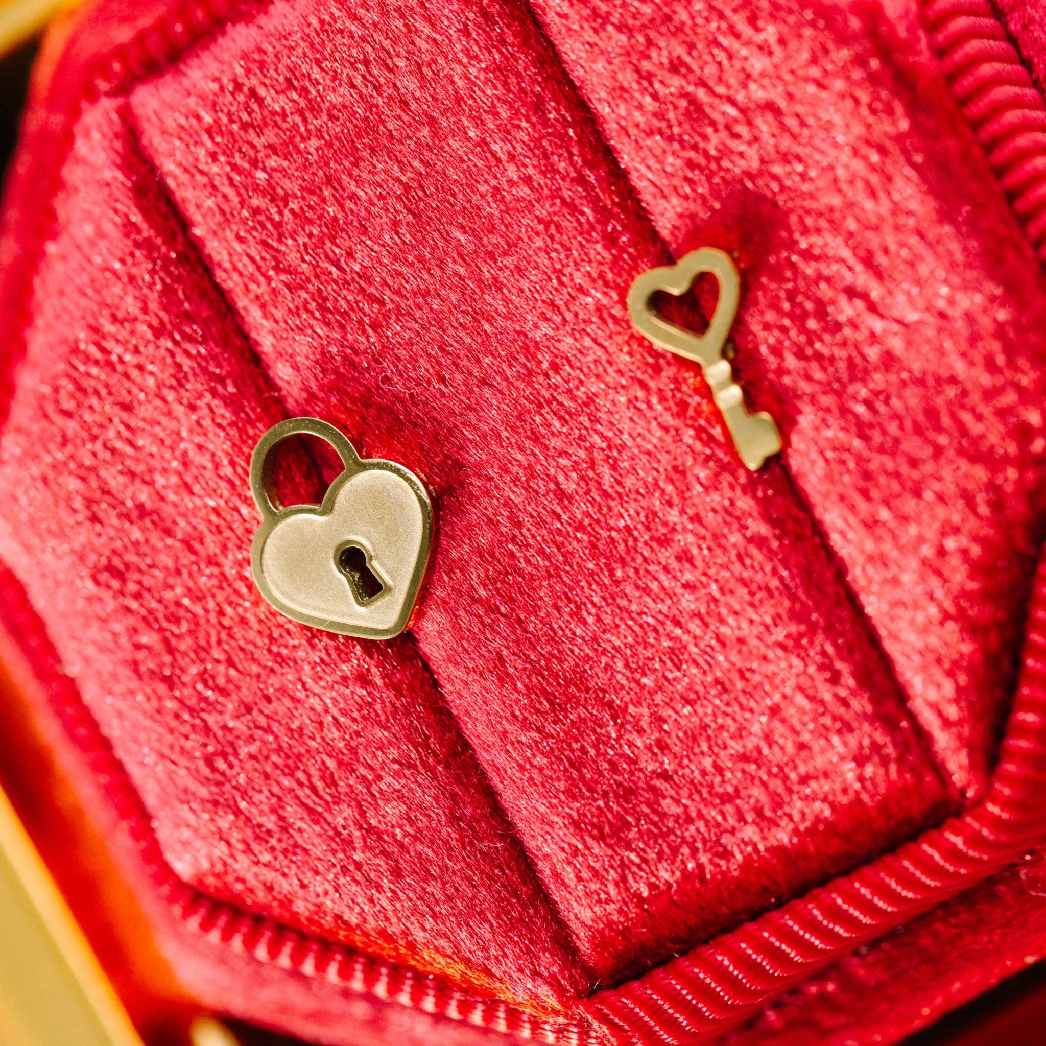 gold heart-shaped lock and key earrings on a red background