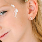 Close-up of a young girl wearing a gold mushroom earring with a winter mushroom design.