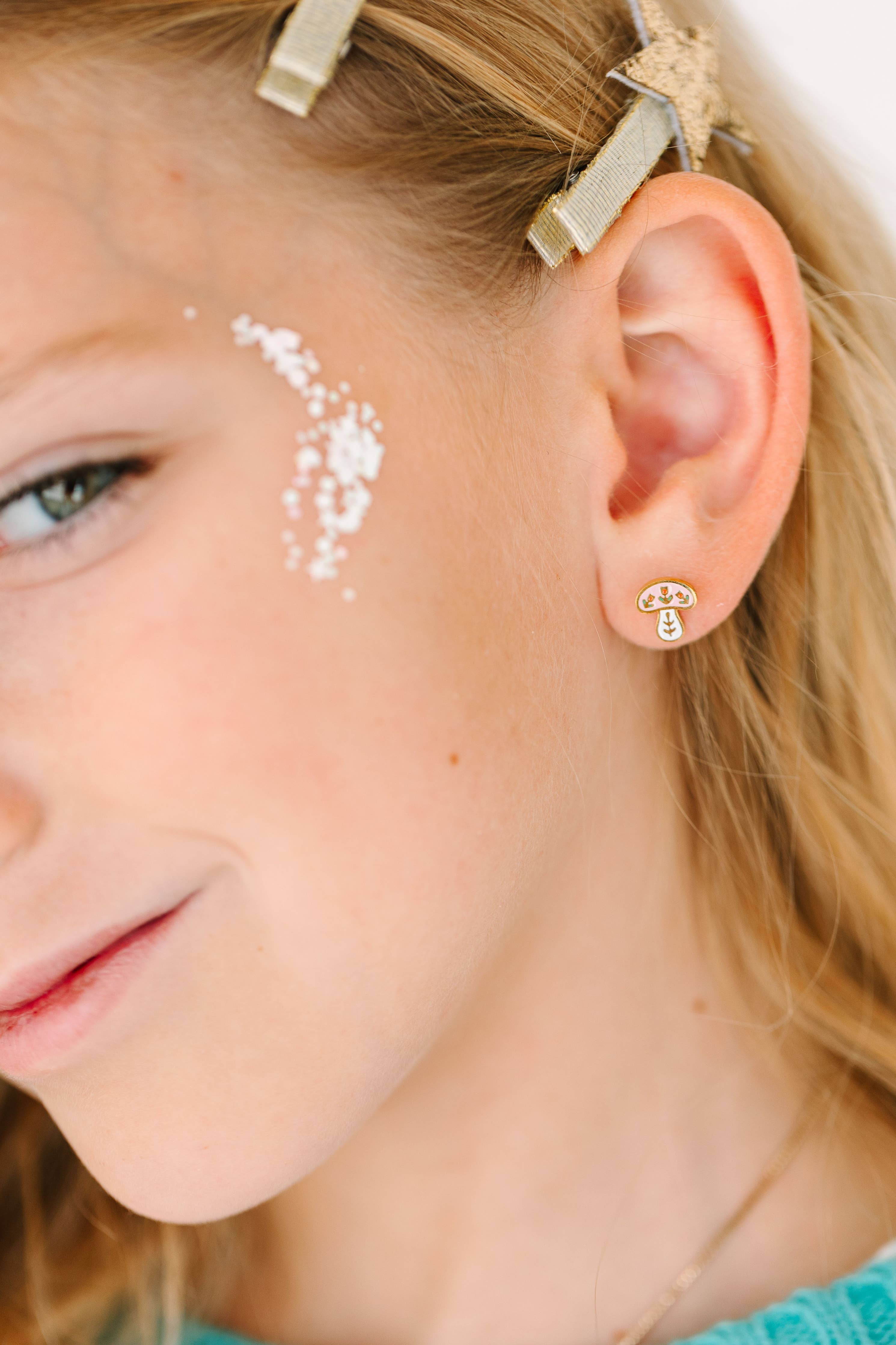 Close-up of a young girl wearing a gold mushroom earring with a winter mushroom design.