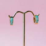 Pair of earrings with opal stones on a pink background