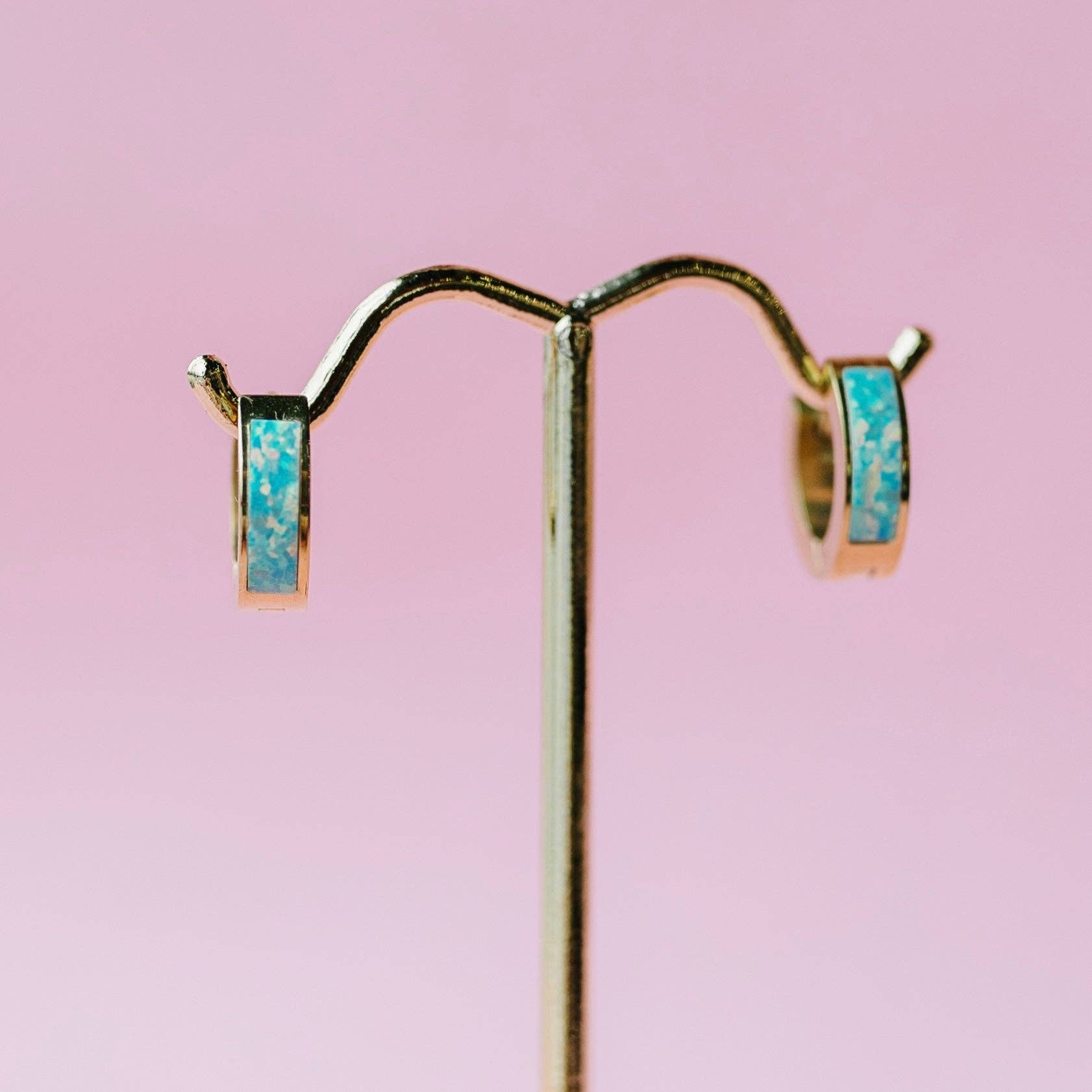 Pair of earrings with opal stones on a pink background