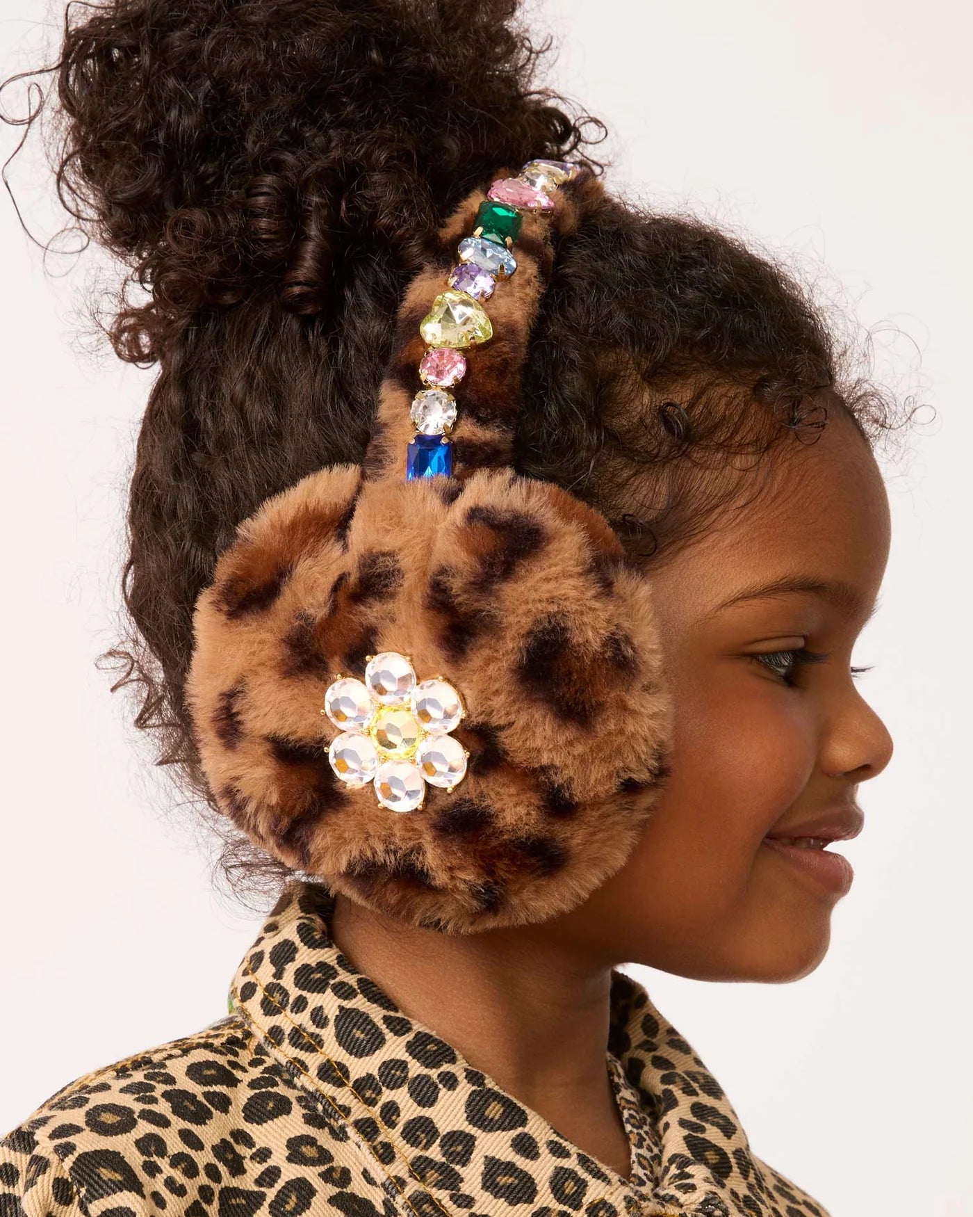 Child wearing a leopard print headband with decorative elements on a plain background