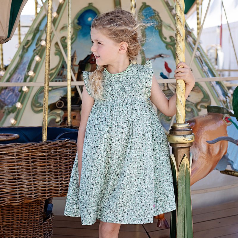 Girl on a carosel wearing green ditsy dress