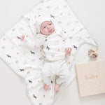 Baby dressed in dog and stripe print clothing laying on top of the dog print baby blanket