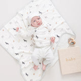 Baby dressed in dog and stripe print clothing laying on top of the dog print baby blanket