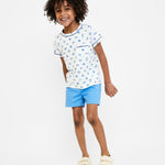 Child wearing a white t-shirt with blue floral pattern and blue shorts on a white background