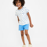 Child wearing a white t-shirt with blue floral pattern and blue shorts on a white background